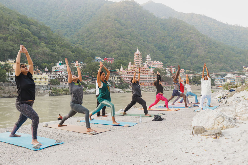 People enjoying an outdoor yoga session close to a river